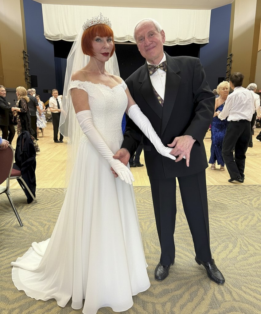 Tibor and Megan of Dance First Calgary dressed for a wedding — Megan in a white gown, veil and tiara, Tibor in a tuxedo — on the ballroom floor